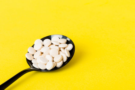 Heap of white pills on colored background. Tablets scattered on a table. Vitamins and dietary supplements concept.の写真素材