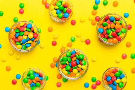 different colored round candy in bowl and jars. Top view of large variety of sweets and candies with...