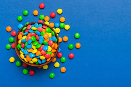 Multicolored candies in a bowl on a colored background. birthday and holiday concept. Top view with...