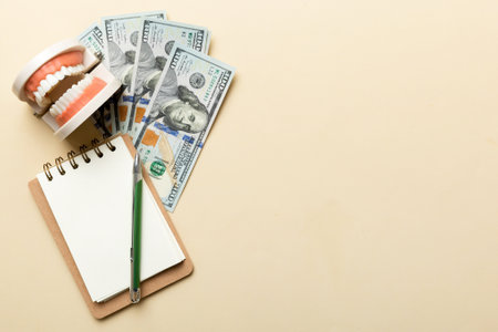 Flat lay composition with educational dental typodont model and money with notebook on colored table, top view. Expensive treatment.の写真素材