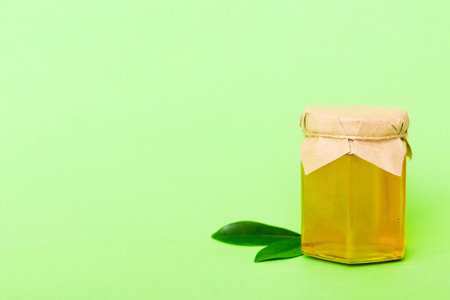 Honey in jar with leaves on colored background top view with copy text.の写真素材