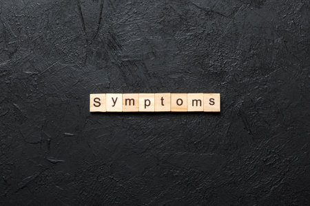 symptoms word written on wood block. symptoms text on table, concept.の写真素材