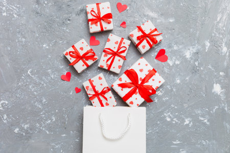 Gift boxes pop out from paper bag top view on colored background. bag packing handmade boxes fall out Concept of holidays, shopping, sale, discounts. Top view, flat lay.の写真素材