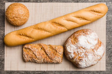Assortment of freshly baked bread with napkin on rustic table top view. Healthy unleavened bread. French bread.の写真素材