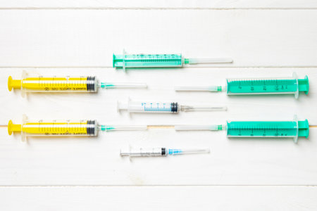 Top view of medical syringes with needles on wooden background with copy space.の写真素材