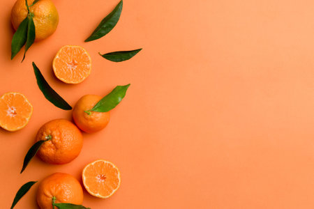 Many fresh ripe mandarin with green leaves on colored background, top view, space for text.の写真素材