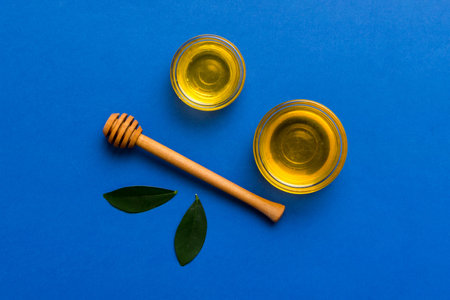 Honey with wooden honey dipper on blue background top view with copy space.の写真素材