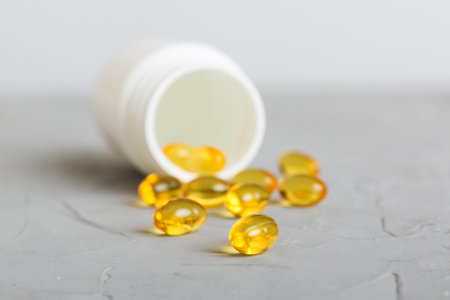 Soft gels pills with Omega-3 oil spilling out of pill bottle close-up. Gel capsules bottle white surface. Omega 3, multivitamins, Calcium. Health. Immunity.の写真素材
