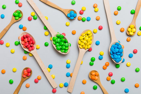 delicious colorful sweet candies on spoon on colored background. Confectionery decor top view with...