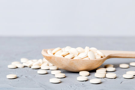 Heap of white pills on colored background. Tablets scattered on a table. Pile of red soft gelatin capsule. Vitamins and dietary supplements concept.の写真素材