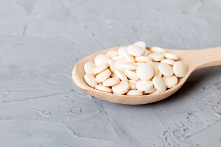 Heap of white pills on colored background. Tablets scattered on a table. Pile of red soft gelatin capsule. Vitamins and dietary supplements concept.の写真素材