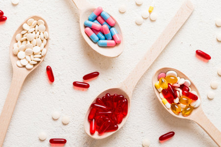 Vitamin capsules in a spoon on a colored background. Red soft gel vitamin supplement capsules on spoon.の写真素材