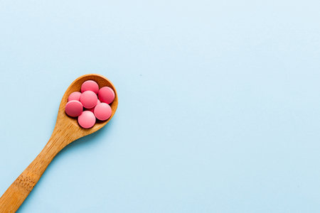 Vitamin capsules in a spoon on a colored background. Pills served as a healthy meal.の写真素材