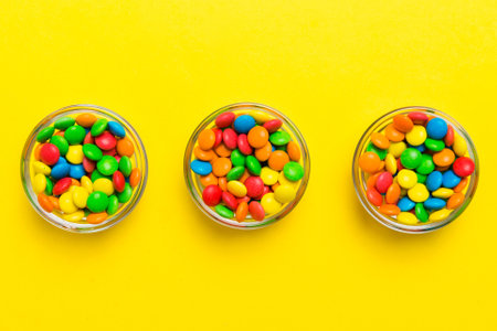 Multicolored candies in a bowl on a colored background. birthday and holiday concept. Top view with copy space.の写真素材