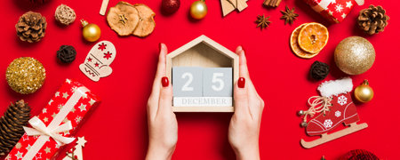Top view of female hands holding calendar on red background. The twenty-fifth of December. Holiday...