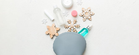 Christmas flat lay with makeup cosmetic products in cosmetic bag on colored background. Top view New year Beauty concept.の写真素材