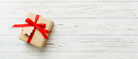 wrapped christmas or other holiday handmade present in paper with colored ribbon. Present box, decoration of gift on colorful table, top view with copy space.の写真素材