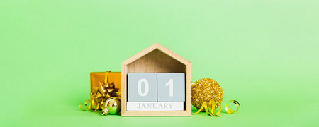 January 1 composition on colored background with a wooden calendar, with a gift box, toys, bauble copy space.の写真素材