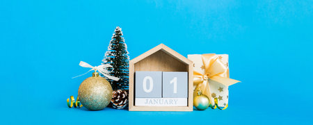 Christmas composition on colored background with a wooden calendar, with a gift box, toys, bauble...