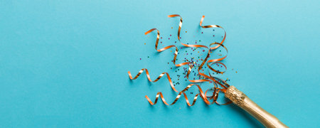 Creative flat lay composition with bottle of champagne and space for text on color background. Champagne bottle with colorful party streamers. holiday or christmas concept.の写真素材