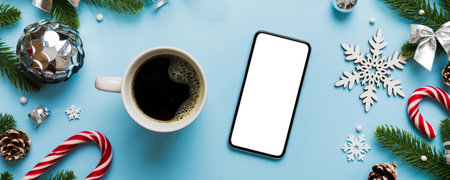 top view of smart phone with hot cup of coffee. Christmas decoration on colored background.の写真素材