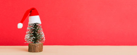 One small Christmas tree with santa hat on colored background. new year decoration with copy space.