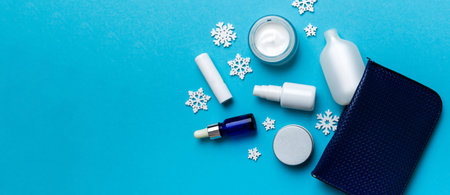 Christmas flat lay with makeup cosmetic products in cosmetic bag on colored background. Top view New year Beauty concept.の写真素材