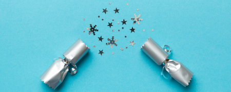 Christmas crackers with shiny confetti on color background, top view, copy space.