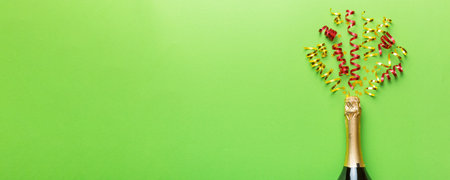 Creative flat lay composition with bottle of champagne and space for text on color background. Champagne bottle with colorful party streamers. holiday or christmas concept.の写真素材