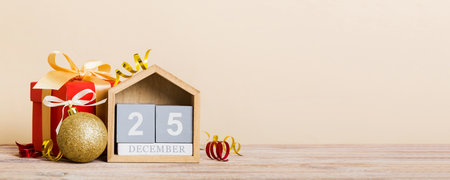 25 december. Christmas composition on colored background with a wooden calendar, with a gift box,...