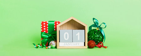 January 1 Christmas composition on colored background with a wooden calendar, with a gift box, toys,...