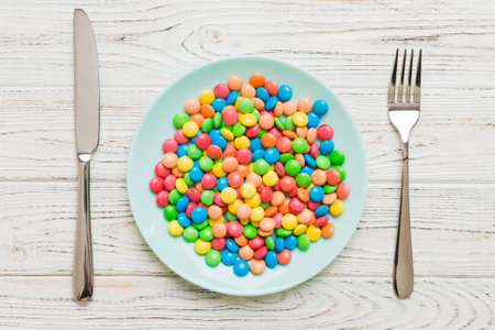 cutlery on table and sweet plate of candy. Health and obesity concept, top view on colored background.の写真素材