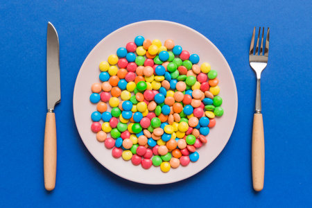 cutlery on table and sweet plate of candy. Top view on colored background.の写真素材