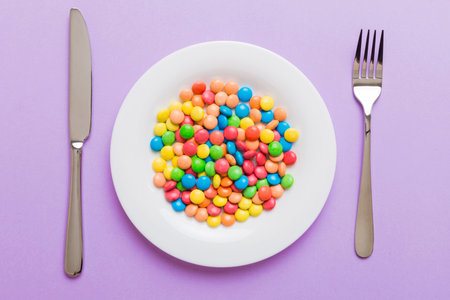 cutlery on table and sweet plate of candy. Top view on colored background.の写真素材
