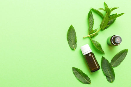 Natural Mint Essential Oil in a Glass Bottle. organic cosmetics with herbal extracts of mint on colored background.の写真素材