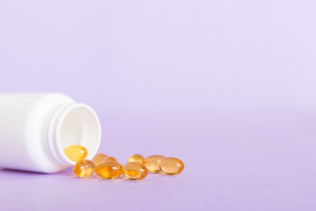 Soft gels pills with Omega-3 oil spilling out of pill bottle close-up. Gel capsules bottle white...