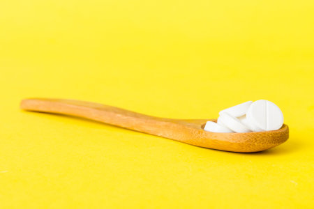Heap of white pills on colored background. Tablets scattered on a table. Pile of red soft gelatin capsule. Vitamins and dietary supplements concept.の写真素材