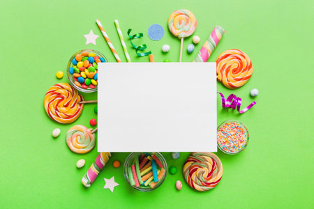 Flat lay holiday composition. Paper blank, lollipop, birthday decorations on Colored background. Top view, copy space for text.の写真素材