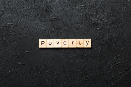 Poverty word written on wood block. Poverty text on cement table for your design, concept.の写真素材