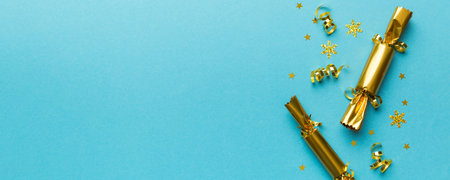 Christmas crackers with shiny confetti on color background, top view, copy space.