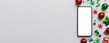 Christmas online shopping from home phone with blank white display top view. smart mobile with copy space on colored background with Christmas decorations balls,. Winter holidays sales background.の写真素材