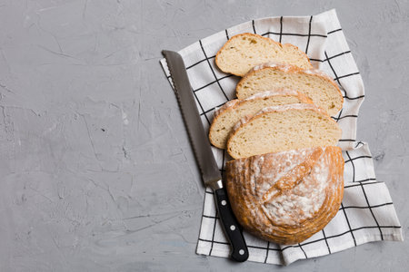 Freshly baked bread cut with knife on a wooden board. top view Sliced bread and knife.の写真素材