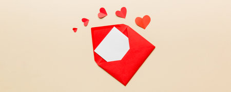 Red paper envelope with empty white card and heart on colored background. top view valentines day concept.の写真素材