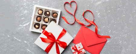 Envelope on colored background for Valentine Day with gift box and chocolate. Heart shaped with gift box of chocolates top view with copy space.の写真素材