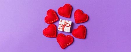 Holiday composition of gift boxes and red textile hearts on colorful background with empty space for...