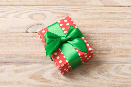 Wrapped christmas or other holiday handmade present in paper with colored ribbon. Present box, decoration of gift on table, top view with copy space.の写真素材