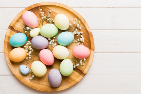 Happy Easter composition. Easter eggs in basket on colored table with gypsophila. Natural dyed...