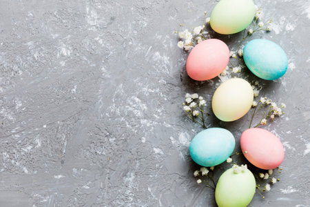 Happy Easter composition. Easter eggs on colored table with gypsophila. Natural dyed colorful eggs background top view with copy space.の写真素材