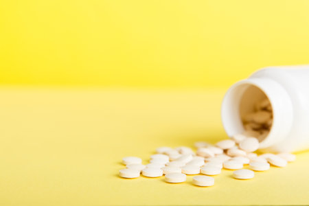 Medicine bottle and white pills spilled on a light background. Medicines and prescription pills flat lay background. White medical pills and tablets spilling out of a drug bottle.の写真素材