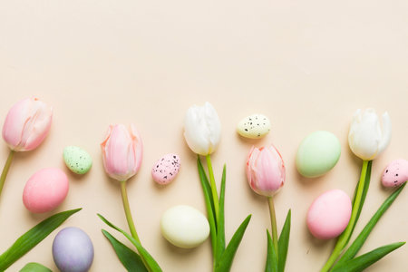 Happy Easter composition. Easter eggs on colored table with yellow Tulips. Natural dyed colorful eggs background top view with copy space.の写真素材